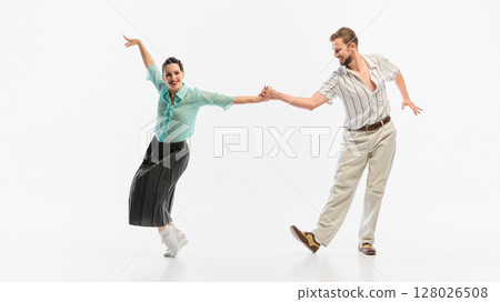 Retro couple energetically dancing in vintage-inspired clothing on white background Retro couple energetically dancing in vintage-inspired clothing on white background 128026508