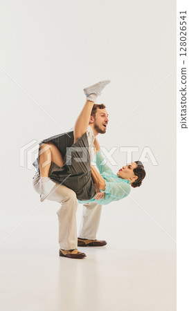 Energetic couple performing lively swing dance move with retro flair. Poster, flyer Energetic couple performing lively swing dance move with retro flair. Poster, flyer 128026541