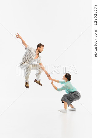Swing dancers mid-air in vintage attire against white background 128026575
