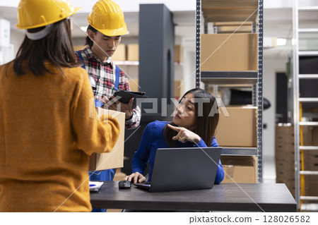 Asian staff members at a fulfillment center printing invoices and prepares packages with bar codes and shipping labels. Small business handles local delivery and in house order processing. Asian staff members at a fulfillment center printing invoices and prepares packages with bar codes and shipping labels. Small business handles local delivery and in house order processing. 128026582