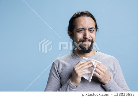 Depressed sad person crying and wiping his tears with tissue on camera, unhappy melancholic guy dealing with low self esteem and an emotional crisis. Young adult feeling distraught, desolation. Depressed sad person crying and wiping his tears with tissue on camera, unhappy melancholic guy dealing with low self esteem and an emotional crisis. Young adult feeling distraught, desolation. 128026682