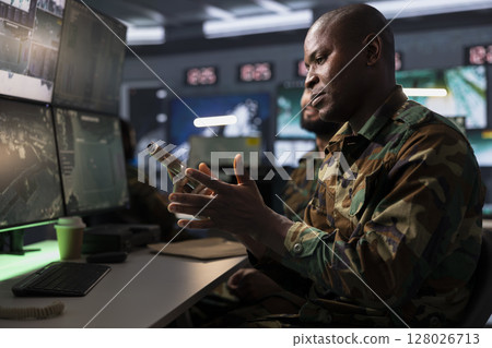 Operative conducing anti terrorism mission, putting bullets in pistol, preparing to attack enemy forces. African american army soldier reloading weapon, preparing to start assault mission Operative conducing anti terrorism mission, putting bullets in pistol, preparing to attack enemy forces. African american army soldier reloading weapon, preparing to start assault mission 128026713
