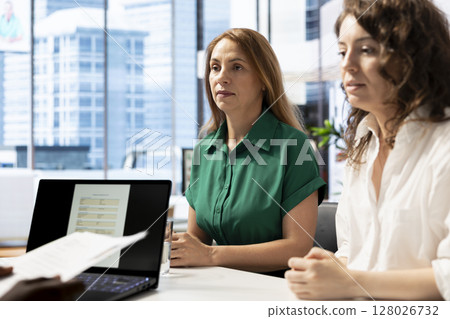 HR staff members reading resume, determining if candidate possesses skills and experience needed to fulfil role. Employer talking with man, checking CV, evaluating if qualifications align with company 128026732