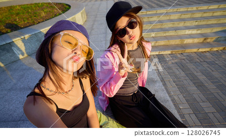 Youthful dancers posing playfully in urban setting with vibrant casual streetwear and accessories 128026745
