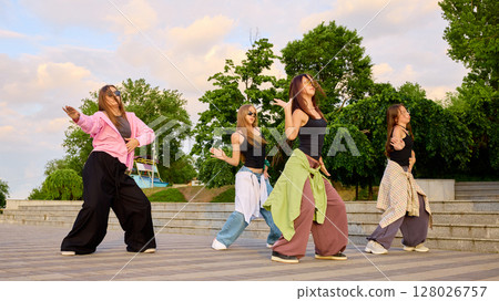 Street dancers performing energetic moves on outdoor paved area 128026757