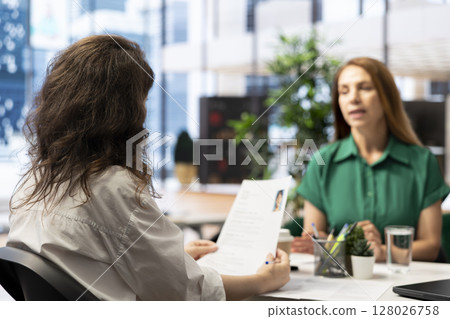 Manager interviewing worker, recruiting for job, discussing business offer in corporate office. Businesswoman hiring candidate after checking CV resume, recruitment concept 128026758