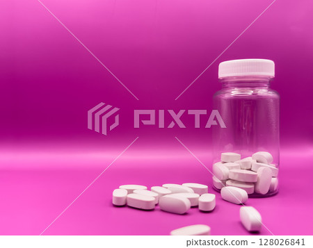 An bottle of white pills. Pills on a pink background. pills studio isolated over white. Covid 19 An bottle of white pills. Pills on a pink background. pills studio isolated over white. Covid 19 128026841