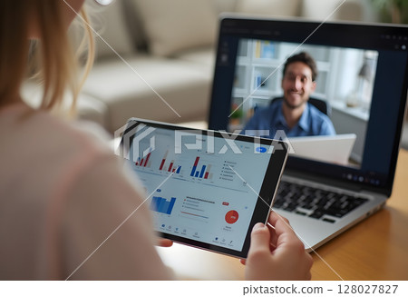 Professional woman in a business suit shows a colorful bar graph chart while video conferencing on a laptop. 128027827