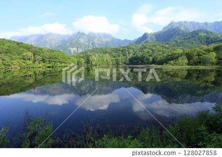 Early summer, Kagami-ike pond on the Togakushi plateau, with the Togakushi mountain range reflected on its surface Early summer, Kagami-ike pond on the Togakushi plateau, with the Togakushi mountain range reflected on its surface 128027858