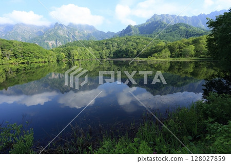 Early summer, Kagami-ike pond on the Togakushi plateau, with the Togakushi mountain range reflected on its surface Early summer, Kagami-ike pond on the Togakushi plateau, with the Togakushi mountain range reflected on its surface 128027859