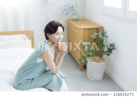 A woman sitting on a bed 128028273