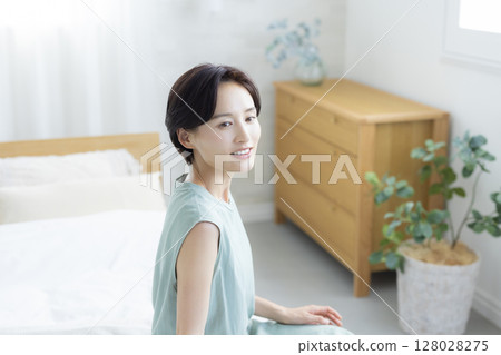 一個女人坐在床上 一個女人坐在床上 128028275