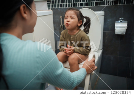 mother is helping toddler girl use the toilet. potty training and learning in bathroom mother is helping toddler girl use the toilet. potty training and learning in bathroom 128028354