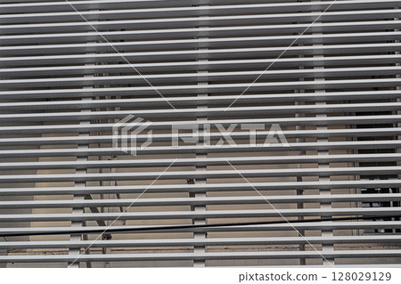 Close-up abstract pattern of horizontal gray metal slats on a building exterior Close-up abstract pattern of horizontal gray metal slats on a building exterior 128029129