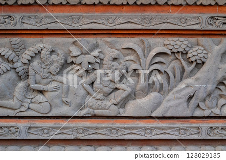 Detailed ancient stone carving artwork showing traditional Balinese mythological scene Detailed ancient stone carving artwork showing traditional Balinese mythological scene 128029185