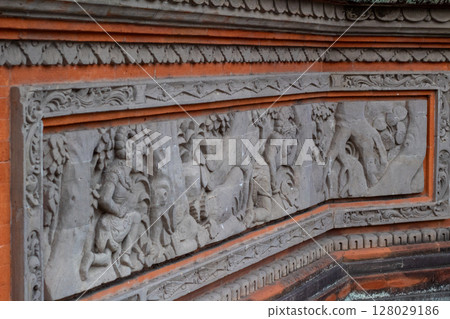Detailed ancient stone carving artwork showing traditional Balinese mythological scene Detailed ancient stone carving artwork showing traditional Balinese mythological scene 128029186