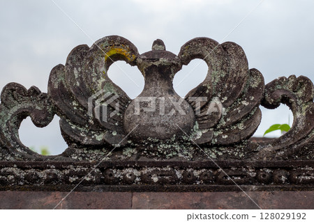 Ancient stone carving detail on a traditional temple roof against a cloudy sky Ancient stone carving detail on a traditional temple roof against a cloudy sky 128029192