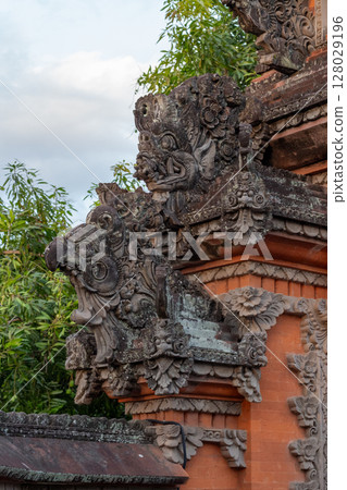Intricate Balinese stone carving detail on ancient temple facade in Indonesia 128029196
