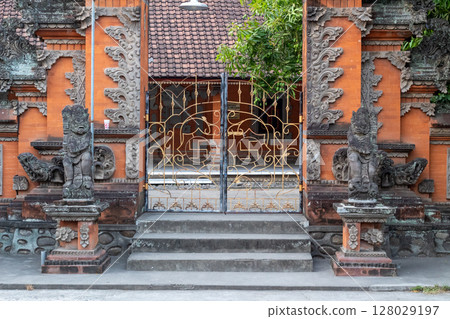 Traditional Balinese Temple Gate with Ornate Stone Carvings and Golden Metalwork Traditional Balinese Temple Gate with Ornate Stone Carvings and Golden Metalwork 128029197