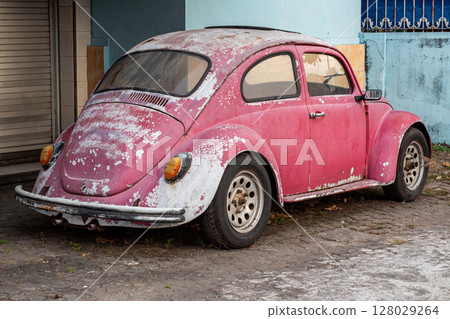 Rear view of an iconic vintage Volkswagen Beetle showing significant paint decay. Rear view of an iconic vintage Volkswagen Beetle showing significant paint decay. 128029264