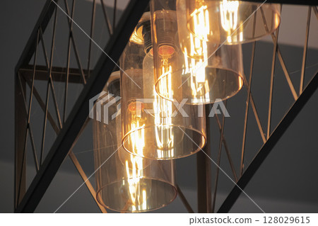 Industrial style geometric pendant light fixture with glowing Edison filament bulb 128029615