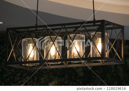Industrial style geometric pendant light fixture with glowing Edison filament bulb 128029616
