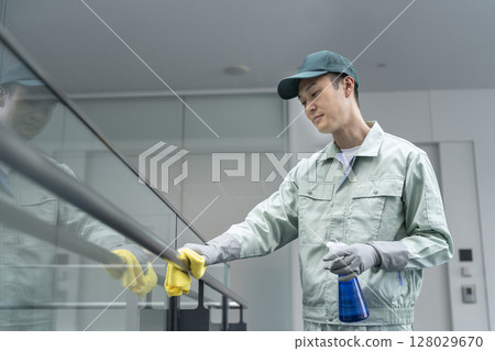 一名中年男性清潔工正在擦拭大樓。圖片為大樓清潔。 128029670