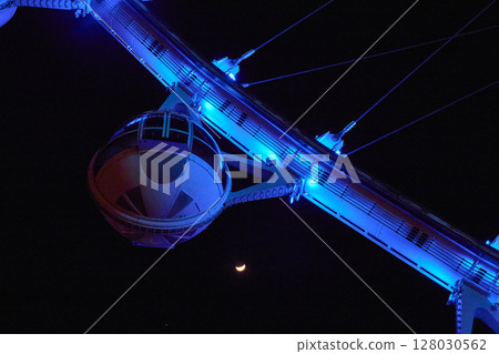 Bright Blue Ferris Wheel with Crescent Moon Night View Looking Up 128030562