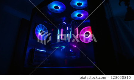 Close-up view of a custom-built computer case with vibrant RGB lighting and cooling fans. 128030810