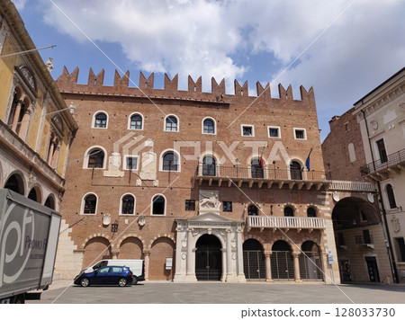 Verona, Italy - May 12, 2025: Palazzo della ragione and torre dei lamberti dominate piazza delle erbe under a cloudy sky in verona, italy Verona, Italy - May 12, 2025: Palazzo della ragione and torre dei lamberti dominate piazza delle erbe under a cloudy sky in verona, italy 128033730