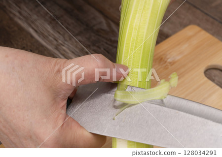 Steps for making vegetable consommé soup: Chop and simmer vegetables. Remove celery strings. 128034291