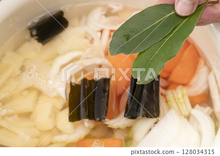 Steps for making vegetable consommé soup: Chop and simmer vegetables, add bay leaves Steps for making vegetable consommé soup: Chop and simmer vegetables, add bay leaves 128034315