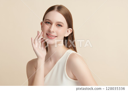 A beautiful young woman with clean, fresh skin against a beige background. Skincare, facial treatment, cosmetology, beauty, and spa. An elegant portrait of an woman. 128035336