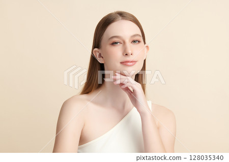 A beautiful young woman with clean, fresh skin against a beige background. Skincare, facial treatment, cosmetology, beauty, and spa. An elegant portrait of an woman. 128035340