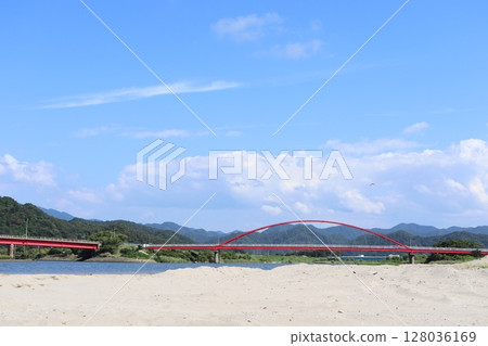 The mouth of the Kishida River, with a long vermilion-painted pedestrian bridge under a bright blue sky 128036169