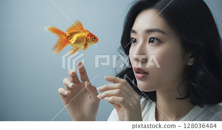 A woman tries to touch a goldfish swimming in the air 128036484