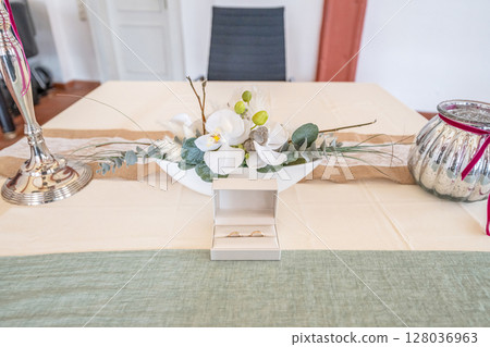 Elegant gold wedding rings lie among soft satin white ribbon. Front vertical view. Mockup for wedding postcard 128036963