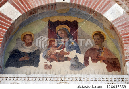 Virgin Mary with baby Jesus and Saints, lunette over the entrance door to the Sant Anastasio church in Lucca, Tuscany, Italy Virgin Mary with baby Jesus and Saints, lunette over the entrance door to the Sant Anastasio church in Lucca, Tuscany, Italy 128037889