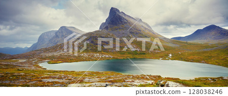 Mountain landscape. Rocky shore of a mountain lake on a rainy autumn morning. Beautiful nature of Norway. Horizontal banner 128038246