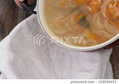 The process of making vegetable consommé soup: Strain the stewed vegetables to remove the soup. 128038433