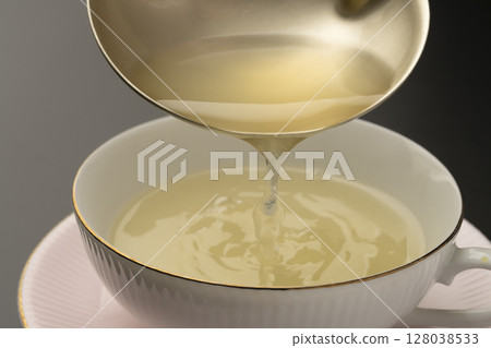 Ladle the vegetable consommé soup into soup cups. Ladle the vegetable consommé soup into soup cups. 128038533