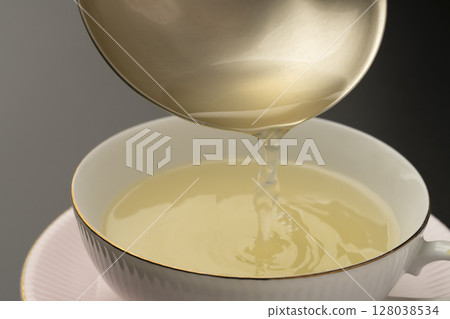 將蔬菜清湯舀入湯杯中。 將蔬菜清湯舀入湯杯中。 128038534