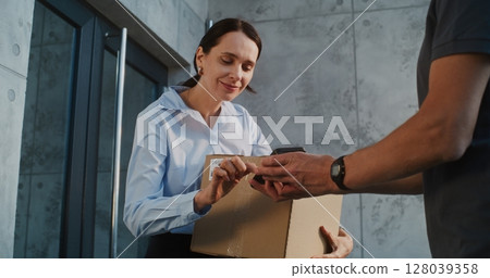 Businesswoman Receiving Package with Online Shopping Order, Signing POD on Smartphone Businesswoman Receiving Package with Online Shopping Order, Signing POD on Smartphone 128039358