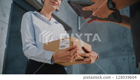 Close Up of Postman Delivering Parcel Box to Addressee, Getting Client's Signature on Digital Tablet 128039604