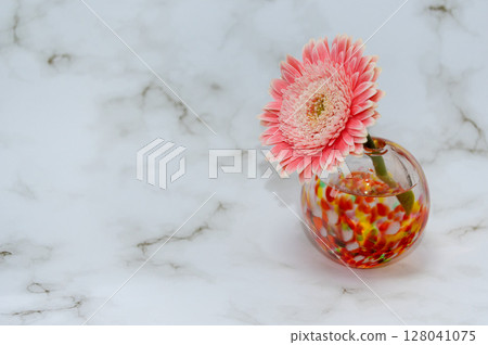 On the right is a gerbera in a glass vase. On the right is a gerbera in a glass vase. 128041075