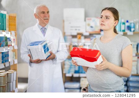 Young pregnant client choosing medical device while pharmacist offering in drugstore 128041295