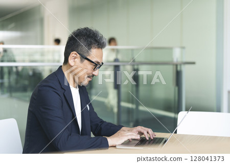 A man in his late 50s working on a laptop computer. Senior businessman image A man in his late 50s working on a laptop computer. Senior businessman image 128041373