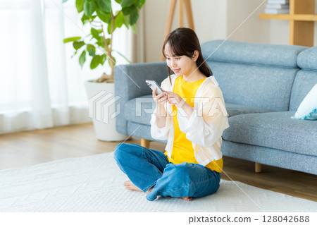 在房間裡操作智慧型手機的年輕女子 128042688