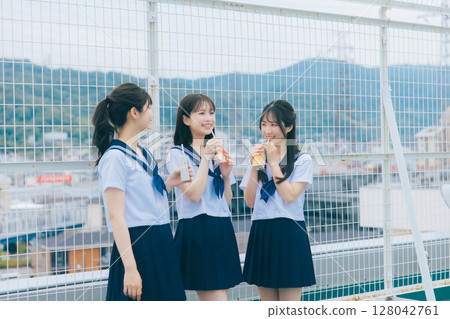 Three high school girls chatting on the roof of the school building 128042761