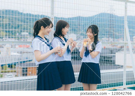 Three high school girls chatting on the roof of the school building 128042766